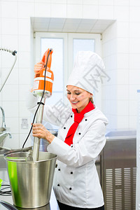 女厨师在烹饪室厨房与食品加工员一图片