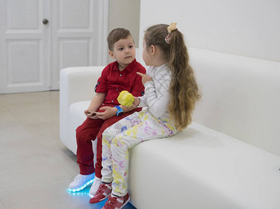 小男孩和女孩坐在沙发上聊天女孩拿着青苹果男孩穿着发光的l图片