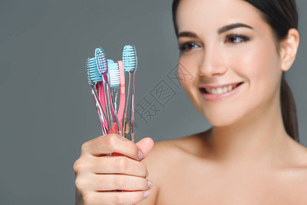 美丽的女人的画像带着牙刷在灰图片