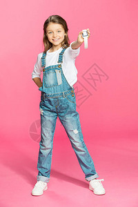 穿着牛仔服的可爱小女孩带着聪明的手表笑着在粉红图片