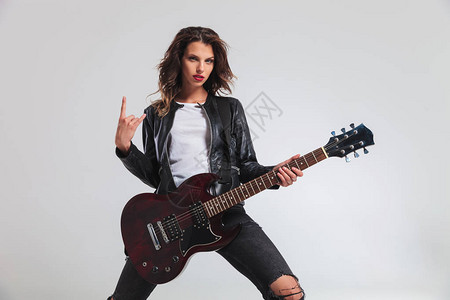 酷的女吉他手在灰色背景上做岩高清图片