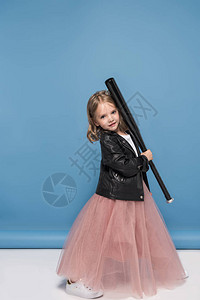穿着皮夹克和粉红色裙子的可爱小女孩拿着棒球棍图片