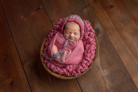 一位6天大的新生女婴睡在木质小碗里图片