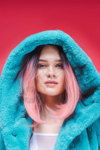 粉红色头发的年轻模特穿着时髦的蓝色皮大衣图片