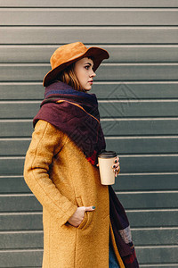 穿着秋夹克和帽子的时髦女人的一面风景带着咖啡图片