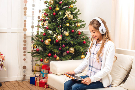 在圣诞节前夕使用数字平板的耳机用耳机装着美丽的图片