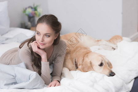 年轻女人和宠物狗躺在图片