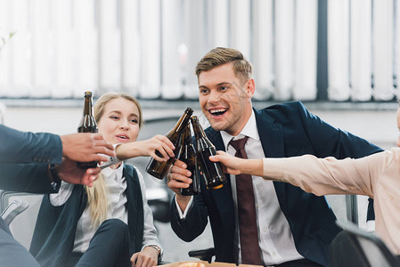 欢乐的年轻同事在办公室喝啤酒瓶时拍图片