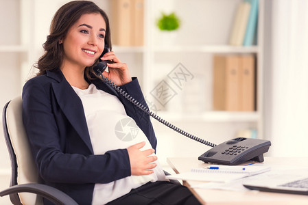 快乐的孕妇在办公室工作时通电话背景图片