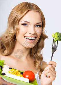 快乐的笑容美丽的年轻女有着健康的素食沙拉图片