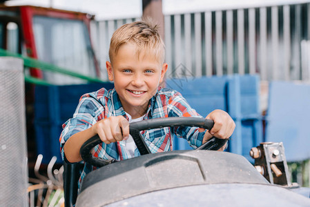 快乐的孩子骑着农用车对着镜头微笑背景图片