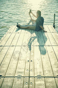 热恋中的情侣坐在码头上自拍图片