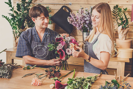 小本生意男和女花店在花店制作玫瑰花束花艺设计工作室的男主人和女助理图片