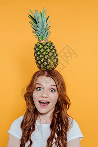 兴奋的红发女孩看着镜头顶披着菠萝在图片