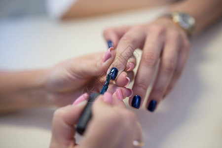 合格的美甲师的手在美甲沙龙里给女客户修指甲女指甲或涂指甲油指图片