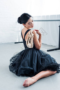 美丽年轻的年轻芭蕾舞女手持尖鞋坐在图片
