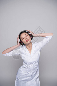 身穿护士服的年轻女半长镜头用大耳机监听音乐图片