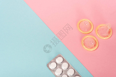 粉色和蓝色表面有避孕药丸和避孕套图片