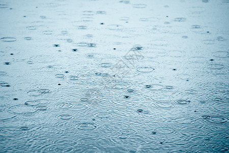 雨滴在蓝天反射的水坑中荡漾图片