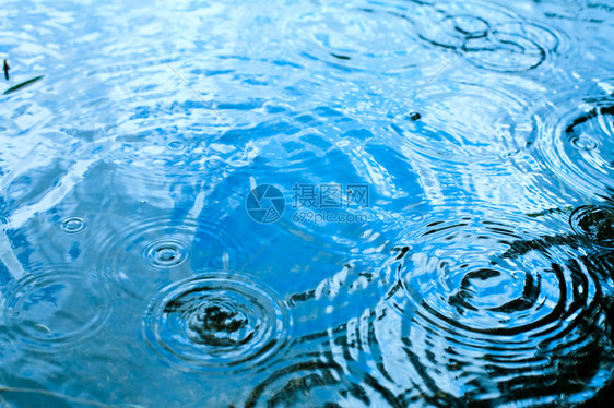 雨滴在蓝天反射的水坑中荡漾图片