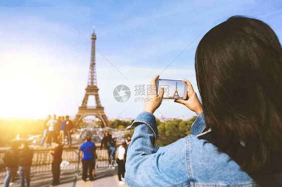 巴黎Eiffel塔附近在阳光和蓝天下通过电话拍照的女旅游者图片
