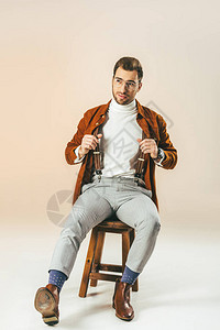 英俊帅的男人在坐木椅子上米色上坐背景图片