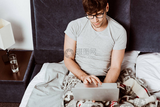 在家床上用笔记本电脑工作的男自由职业图片