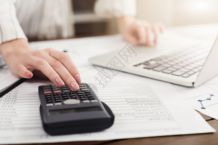 年轻女管理财务审查笔记本电脑和计算器的银行账户在线纳税复背景图片