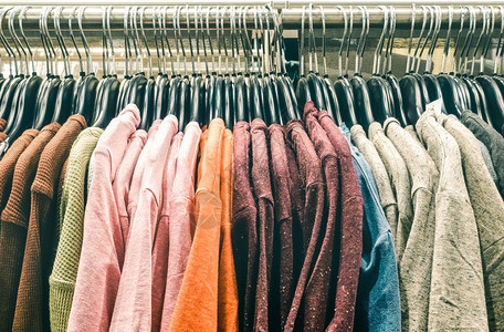 二手套头衫挂在跳蚤市场商店的旧货店时髦衣橱销售概念和另类复古时尚造型柔和对比去饱和背景图片