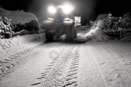 深夜在郊区公路上清除雪的模糊图片