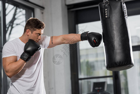在健身房里用打拳袋练习的英俊肌肉图片