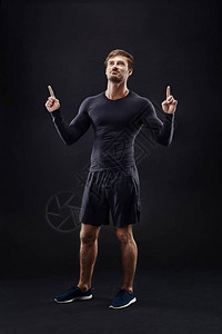 在黑色背景与复制空间的积极运动服的男模特摆在黑色背景上背景图片