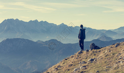 孤单的徒步者站在远方的山上探图片