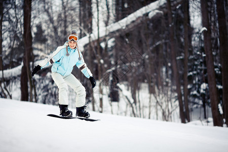 年轻女滑雪者滑下斜图片