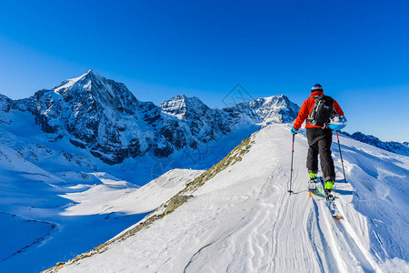 登山者偏远地区滑雪沿着雪脊行走图片