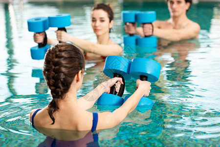 在游泳池与男女一起从事有氧水运动时图片