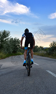 骑自行车的人在日落时沿着一条偏僻的道路背景图片