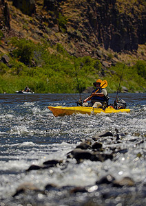 男子划着皮划艇在荒野河流的图片