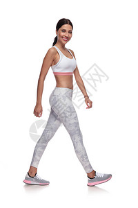微笑感的女人走到一边在白色背景上的运动服她穿着一条白色紧身图片