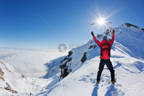 登山者在一个阳光明媚的冬日到达一座雪山之巅图片