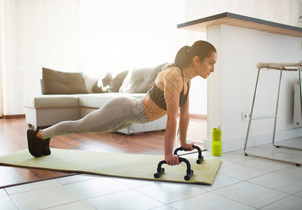 年轻女子在隔离期间在房间里做运动锻炼强壮的健身模型使用俯卧撑手杆站在木板位置的图片一个人图片
