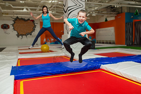 快乐的家庭在母亲和一个男孩的蹦床上跳跃和玩耍在体育图片