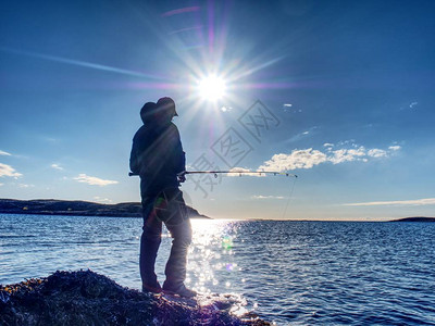 日落时的渔夫剪影渔夫检查钓鱼线并将诱饵推到鱼竿上背景图片