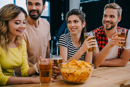 一群带着啤酒和一碗薯片的笑朋友在看足球比赛时背景图片