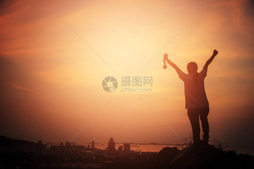 月光女神举手领金牌仰望城市的夕阳胜利概念商业成功图片