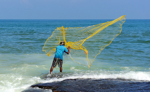 投掷黄色渔网的渔夫图片