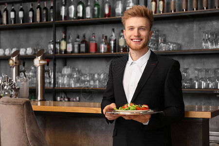 餐厅里有菜的年轻男服务员图片