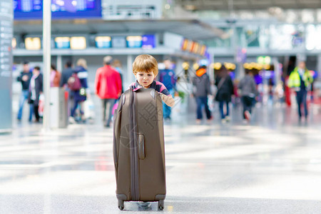 可爱的小男孩带着大手提箱在机场散步图片