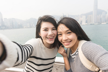 亚裔年轻女孩在香港维多利亚港和朋友玩自图片