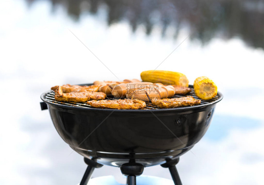 在海滩烧烤在木炭水壶烤架上烹饪食物夏季户外烧烤的香肠肉玉米和蔬菜烧烤派对野图片